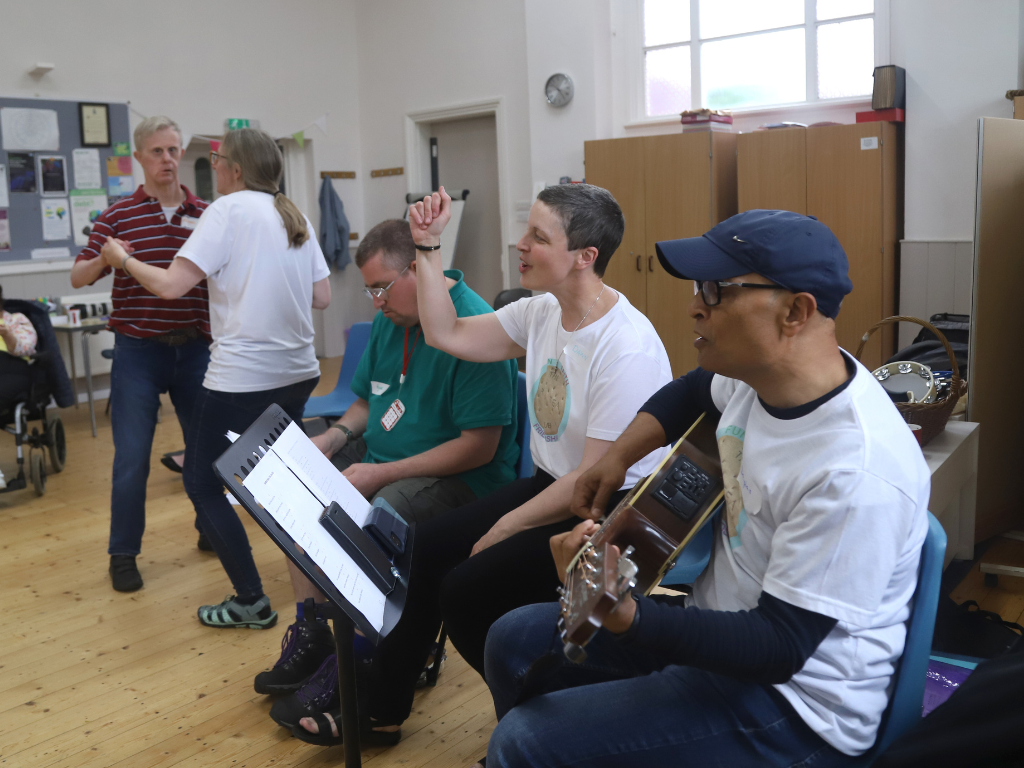 Dawn's voice fills the room as she sings along, accompanied by Douglas on guitar, bringing joy and music to the fellowship gathering